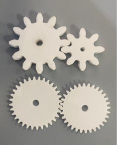 Four laser cut acrylic gears of different sizes on a workbench